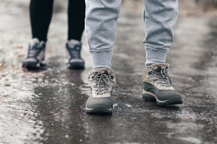 Two people walk along an icy path in winter wearing sturdy walking shoes.